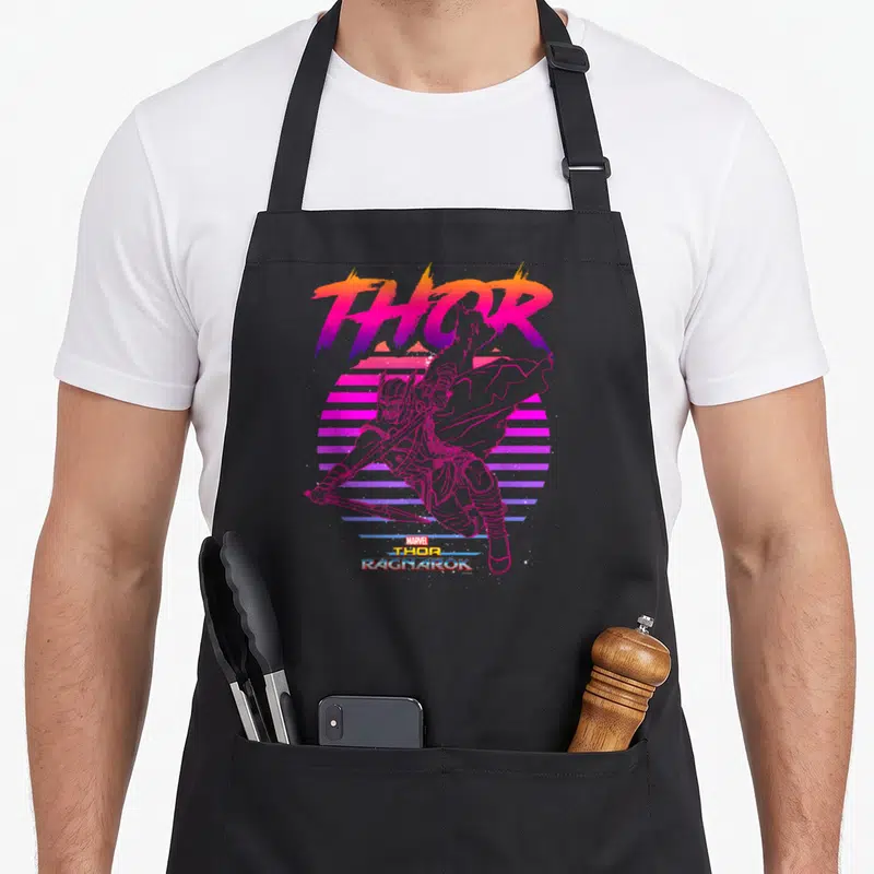 Ragnarok 80s apron - Thor leaping before striped retro sun with pink purple orange yellow THOR RAGNAROK lettering — shown on a black cotton canvas apron against a white background