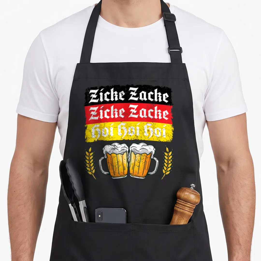 Clothe german apron - Zicke Zacke Hoi Hoi Hoi German flag text above two beer mugs and wheat stalks in retro style — shown on a black cotton canvas apron against a white background
