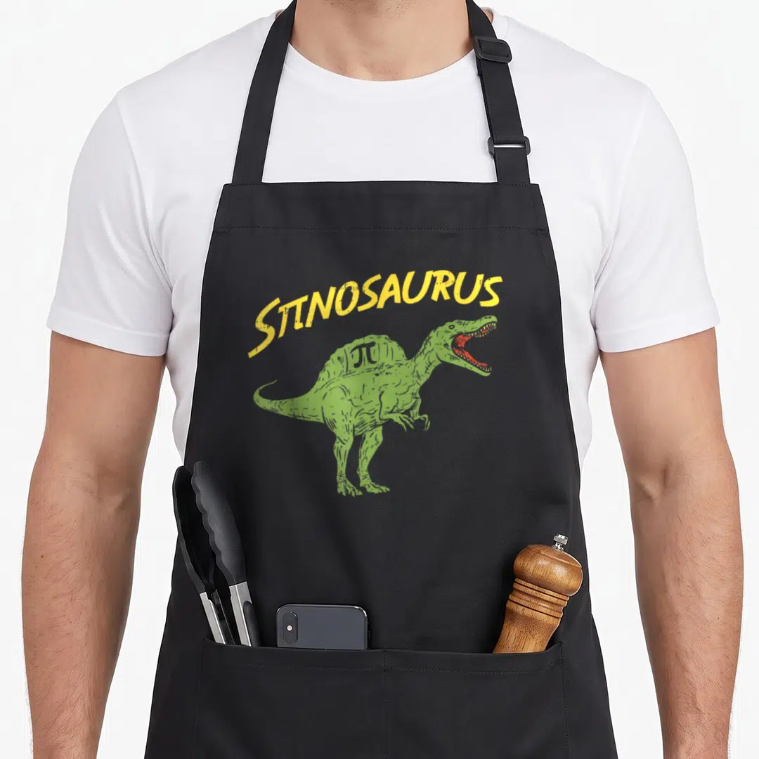 Math dinosaur apron - Green Spinosaurus with yellow pi symbol and arched πTINOSAURUS text — shown on a black cotton canvas apron against a white background