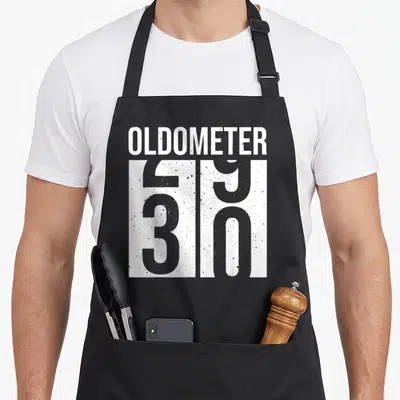 Vintage 30th birthday apron - White OLDOMETER text above a large number 50 on a black background — shown on a black cotton canvas apron against a white background