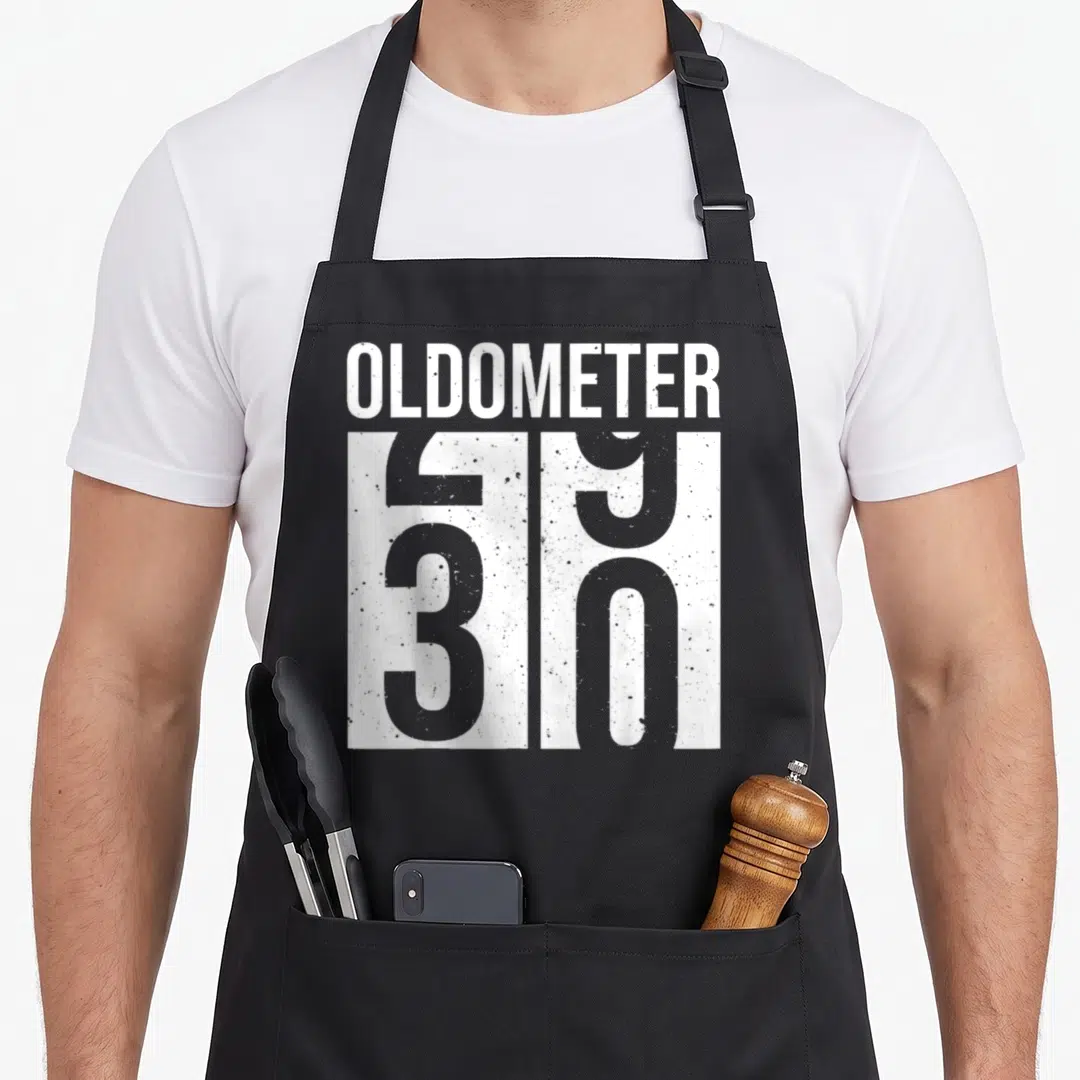 Vintage 30th birthday apron - White OLDOMETER text above a large number 50 on a black background — shown on a black cotton canvas apron against a white background