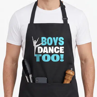 Bold ballet dance apron - White dancer silhouette overlapping stacked light blue and white text reading Boys Dance Too — shown on a black cotton canvas apron against a white background