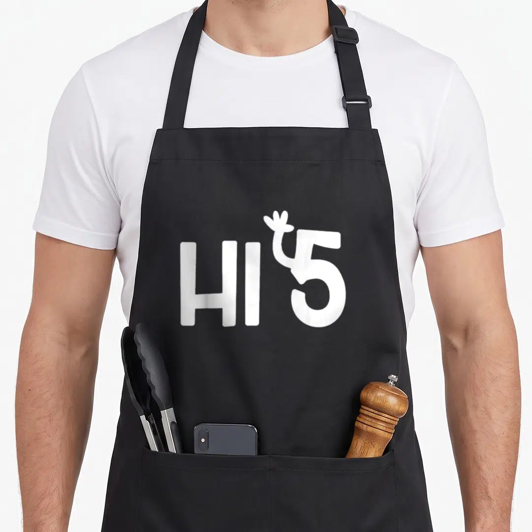 Five joke apron - White HI5 text with hand rising from the five on dark background — shown on a black cotton canvas apron against a white background