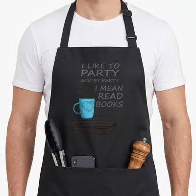Mean book apron - Blue mug with heart on two stacked books with steam and quote text — shown on a black cotton canvas apron against a white background