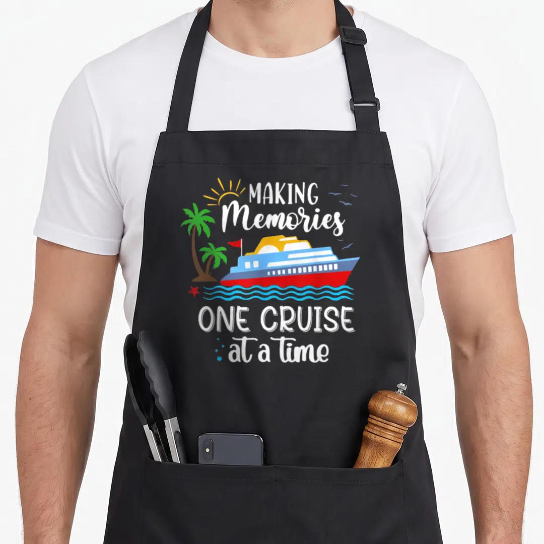 Cruise memory apron - Cartoon cruise ship on blue waves with palm trees and text Making Memories One Cruise At A Time — shown on a black cotton canvas apron against a white background