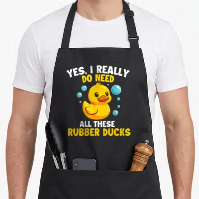 These rubber do i need an apron - Cartoon yellow duck with blue bubbles and text Yes I Really Do Need All These Rubber — shown on a black cotton canvas apron against a white background