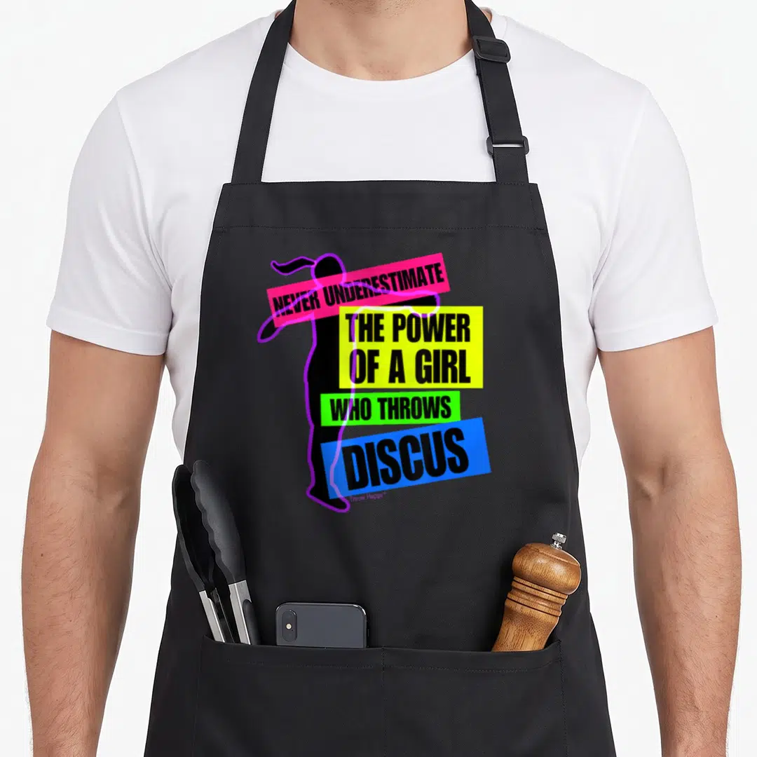 Power track apron - Black girl silhouette with pink yellow green blue purple text blocks reading NEVER UNDERESTIMATE — shown on a black cotton canvas apron against a white background
