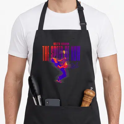 Speed parts of an apron - Keith Urban The Speed of Now Part 1 retro guitarist print in red blue purple — shown on a black cotton canvas apron against a white background