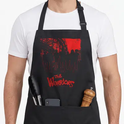 Warrior kitchen island apron - Seven grey silhouettes with red outline below red bridge structure and THE Warriors text — shown on a black cotton canvas apron against a white background