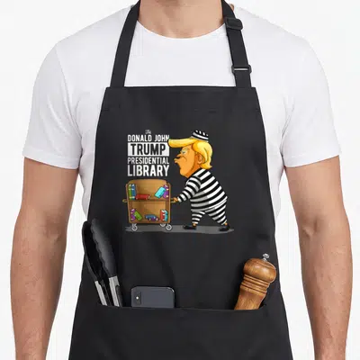 Prison option funny apron - Cartoon man in striped uniform pushing brown book cart next to stacked text reading — shown on a black cotton canvas apron against a white background