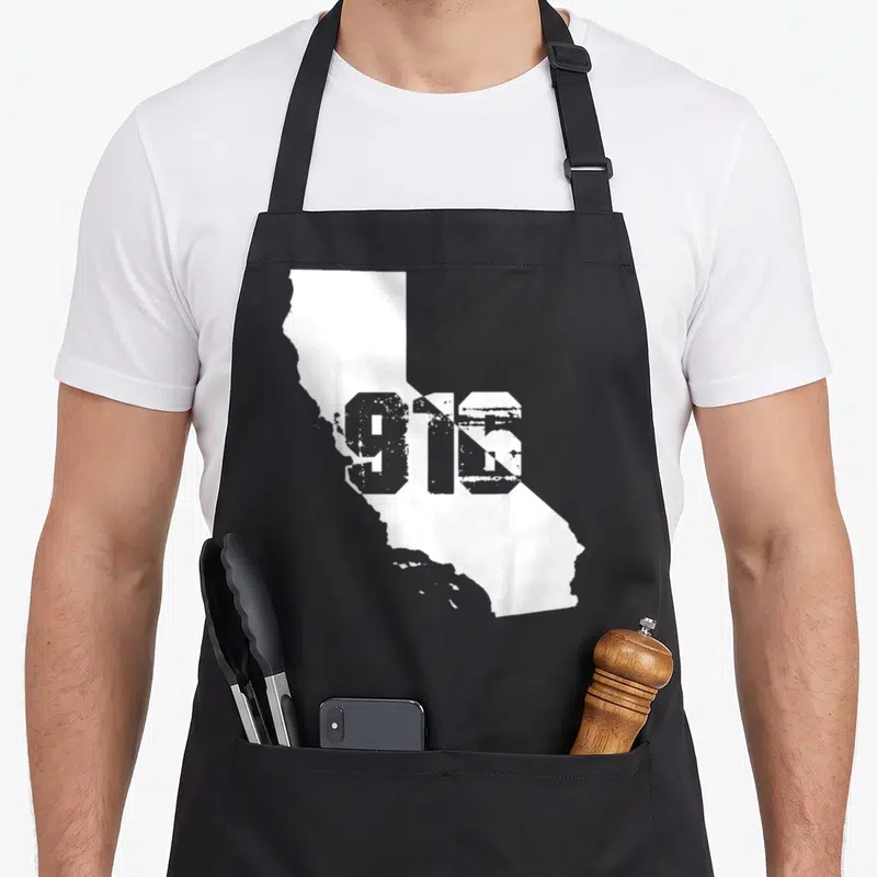Area sacramento apron - Grey 916 text over white California state outline with distressed texture — shown on a black cotton canvas apron against a white background