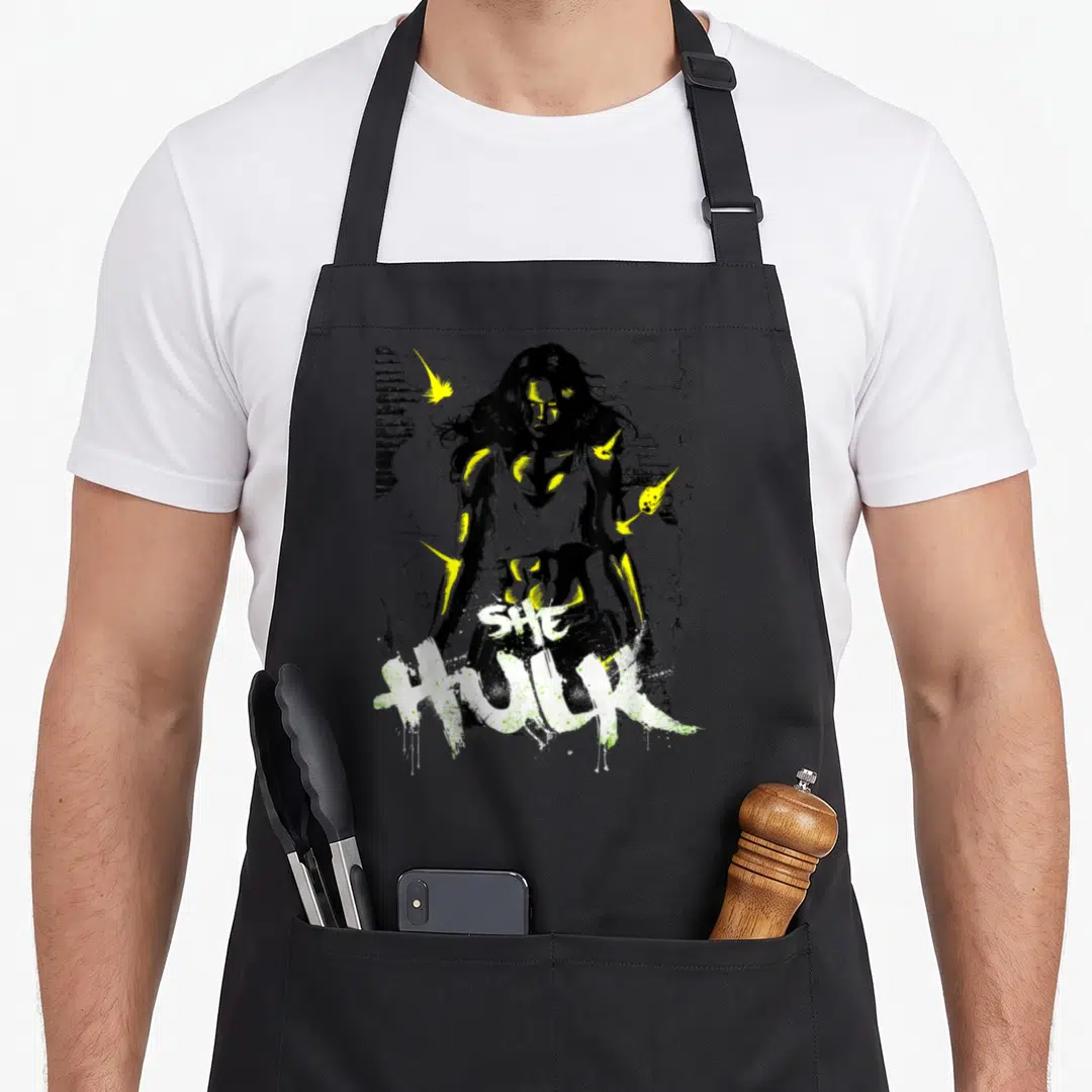 Neon savage apron - Stylized woman with yellow bolts and SHE HULK text in black white grey cartoon art — shown on a black cotton canvas apron against a white background
