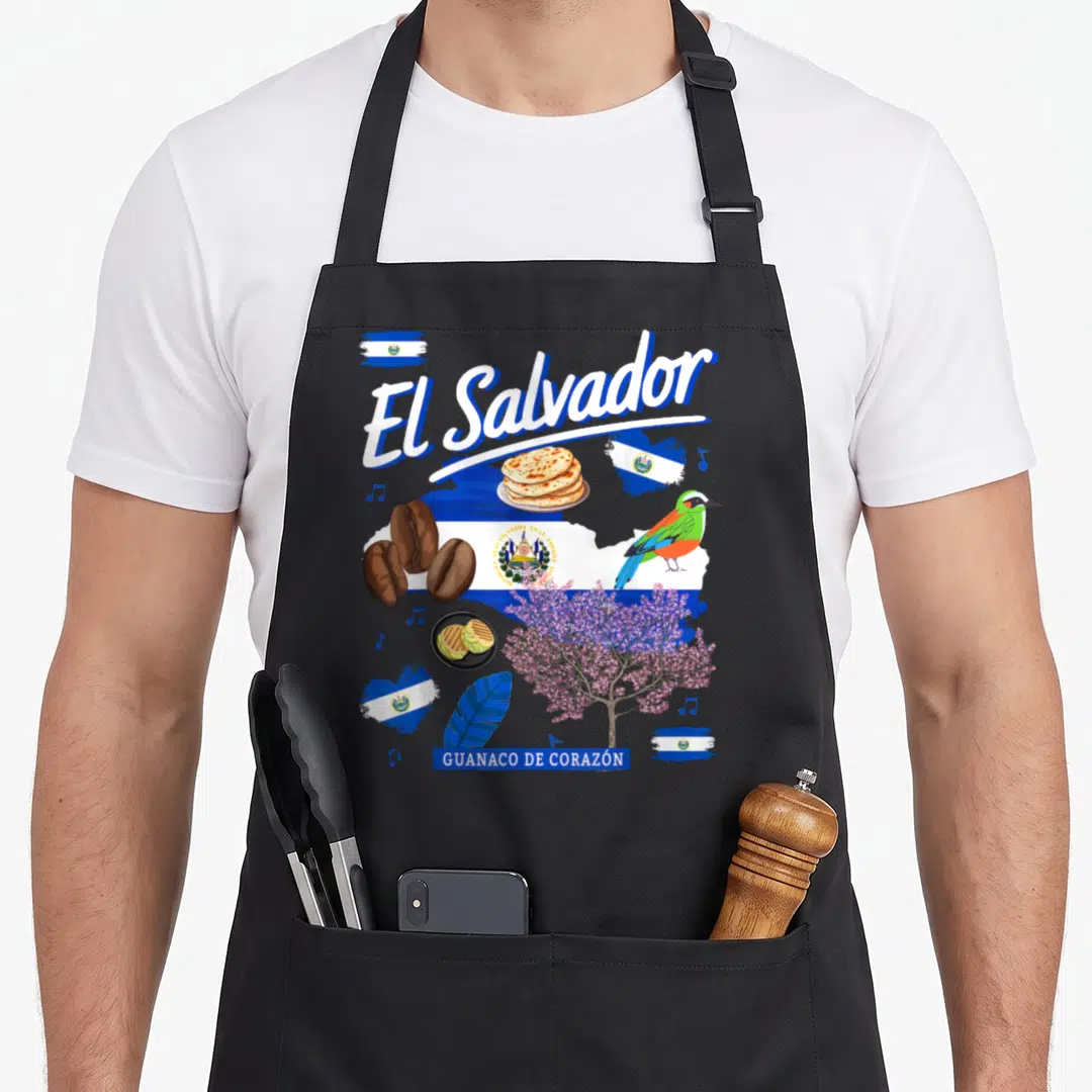 Salvador chef outfit with apron - El Salvador text, pupusas, coffee beans, quetzal bird, and flag elements in blue — shown on a black cotton canvas apron against a white background