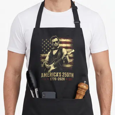 Abraham 250th 4th of july apron - Abraham Lincoln playing guitar over distressed red and gold flag with America's 250th — shown on a black cotton canvas apron against a white background