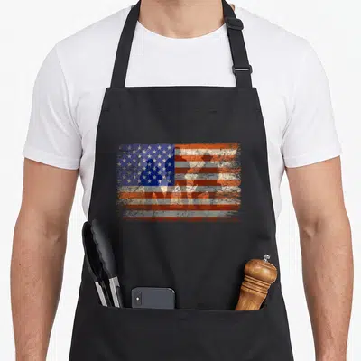 Military soldier patriotic apron - Four soldier silhouettes overlaid on a distressed red white and blue American flag — shown on a black cotton canvas apron against a white background