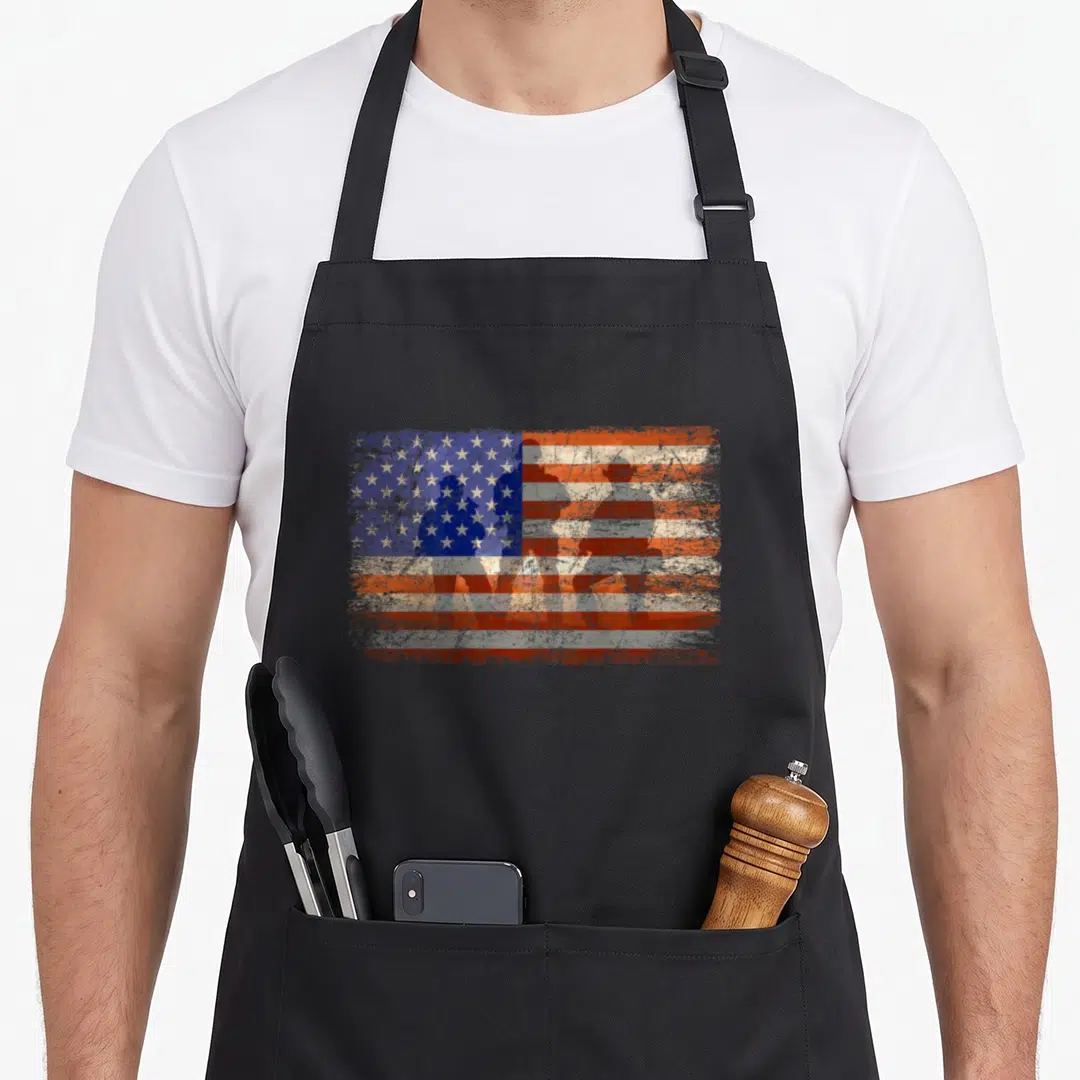 Military soldier patriotic apron - Four soldier silhouettes overlaid on a distressed red white and blue American flag — shown on a black cotton canvas apron against a white background