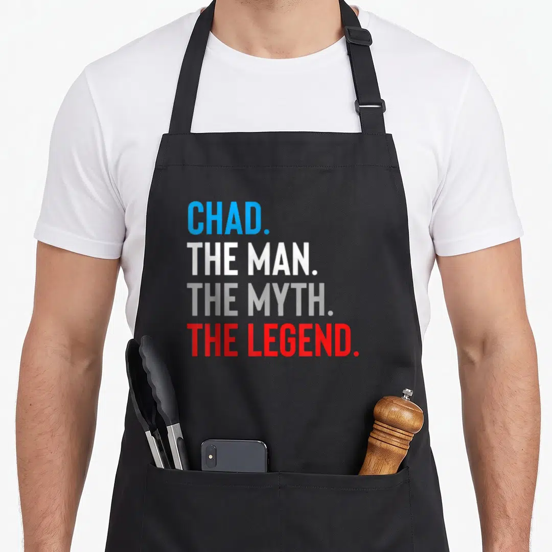 Myth chad apron - Stacked text reading CHAD THE MAN THE MYTH THE LEGEND in blue white grey and red — shown on a black cotton canvas apron against a white background