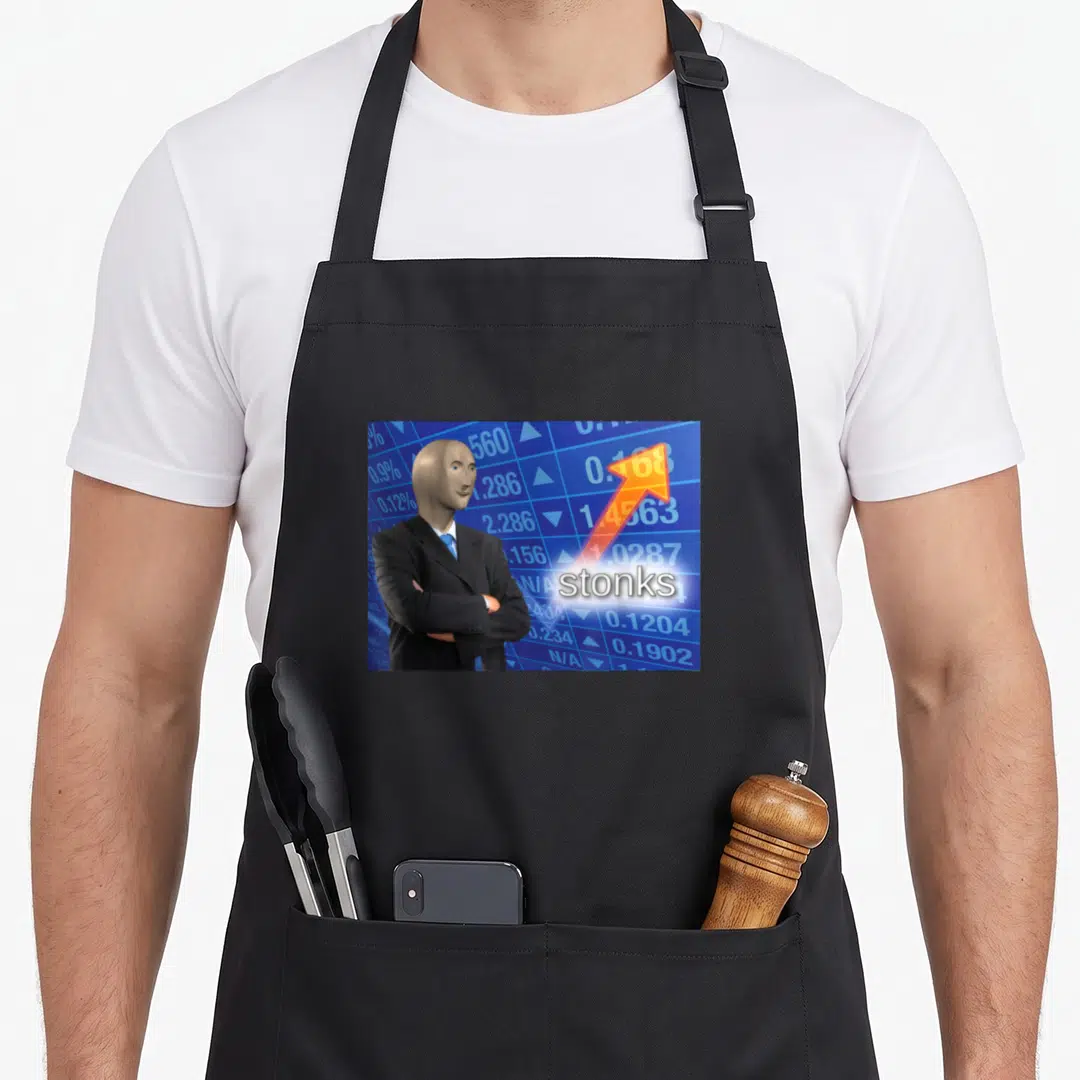 Stonk meme apron - Meme Man in suit on blue chart with orange arrow and stonks text in white box — shown on a black cotton canvas apron against a white background