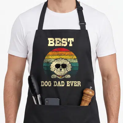 Tenerife dog apron - Retro dog in sunglasses over striped sun with Best Dog Dad Ever text — shown on a black cotton canvas apron against a white background