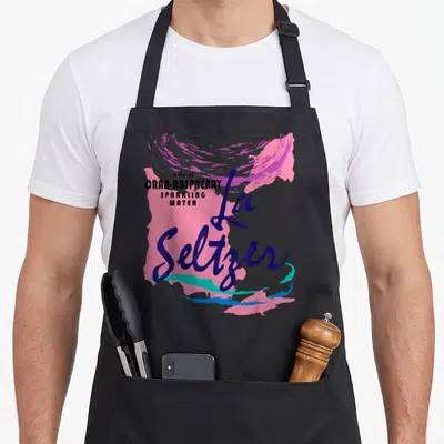 Cranberryraspberry halloween apron - Stacked typography reading natural cran-raspberry sparkling water over pink — shown on a black cotton canvas apron against a white background