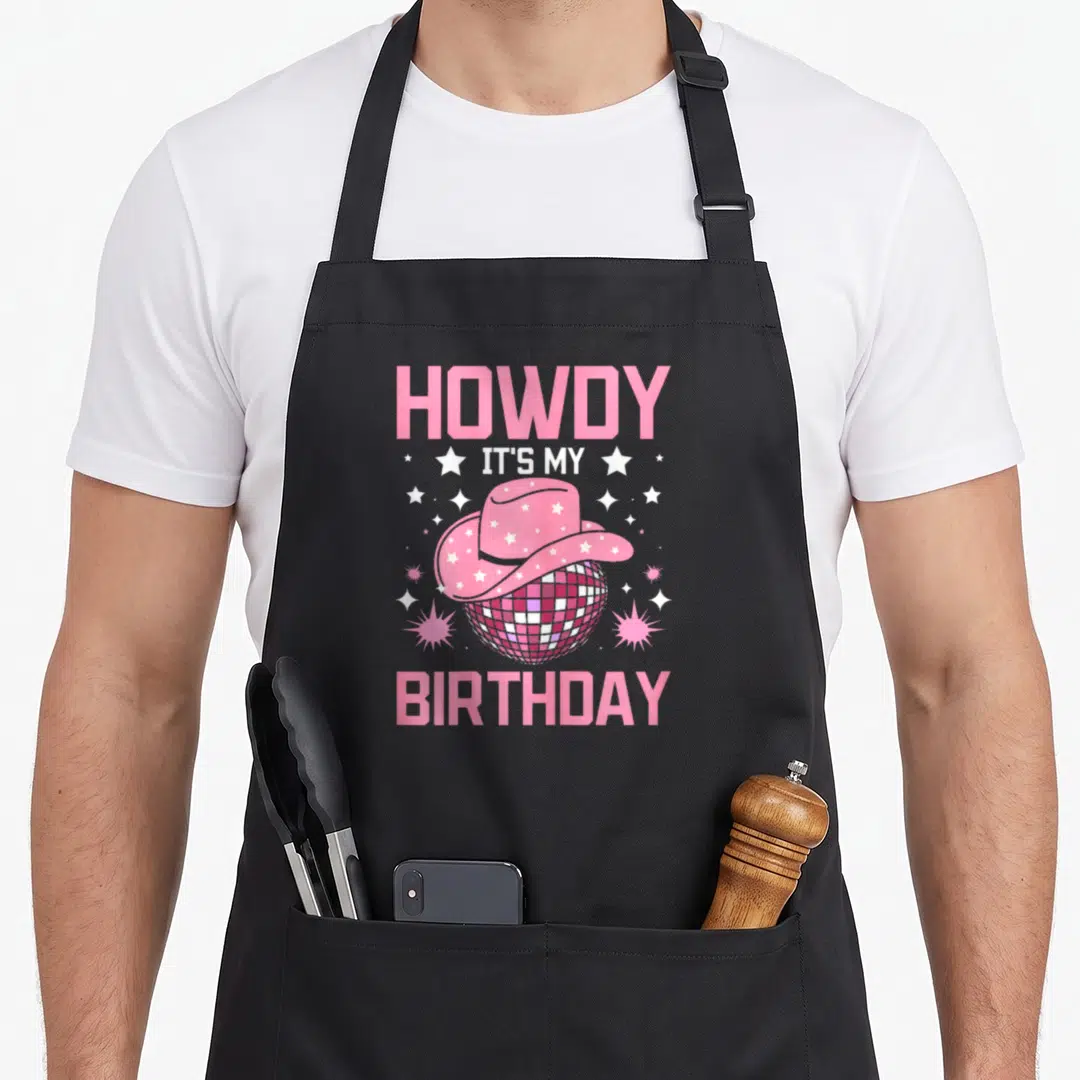 Howdy cowgirl aprons - Pink cowboy hat on disco ball with stars and birthday text — shown on a black cotton canvas apron against a white background