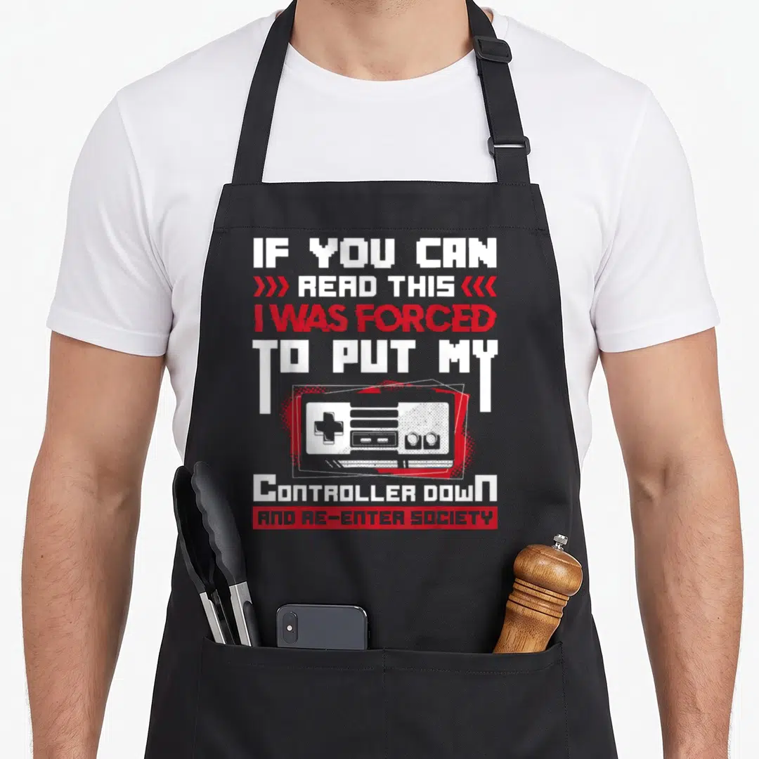 Controller gaming apron - Pixelated white and red text with retro game controller illustration and sarcasm quote — shown on a black cotton canvas apron against a white background