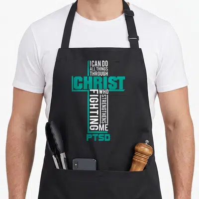 Christ ptsd awareness apron - Teal and white cross typography reading I CAN DO ALL THINGS THROUGH CHRIST WHO — shown on a black cotton canvas apron against a white background