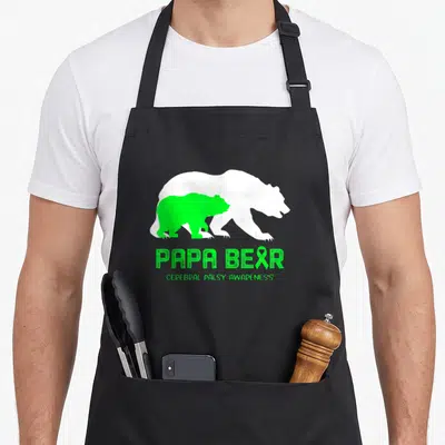 Cerebral bear apron - Green and white nested bear silhouettes with PAPA BEAR text and ribbon A on black background — shown on a black cotton canvas apron against a white background