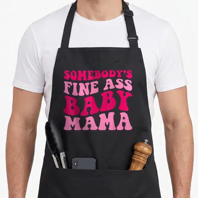Somebody mama apron - Stacked pink text reading SOMEBODY'S FINE ASS BABY MAMA on black background — shown on a black cotton canvas apron against a white background