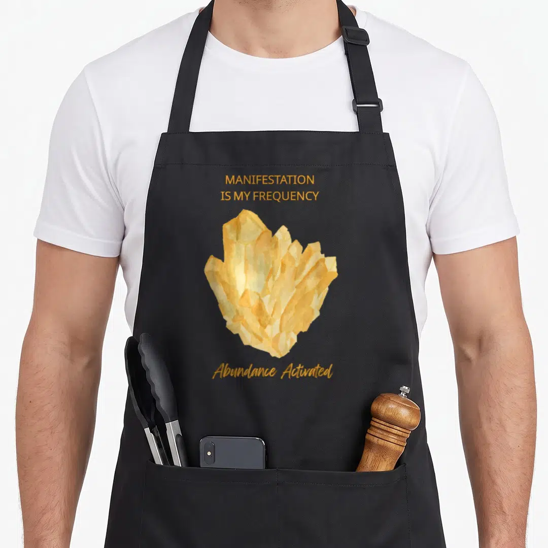 Frequency manifestation apron - Gold watercolor crystal cluster with MANIFESTATION IS MY FREQUENCY text — shown on a black cotton canvas apron against a white background
