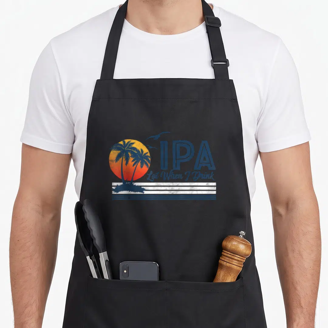 Lot craft apron - Retro beach sun palm trees birds IPA Lot When I Drink text — shown on a black cotton canvas apron against a white background