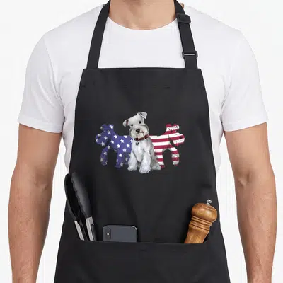 Unique schnauzer apron - Three dogs standing side-by-side in white, blue with stars, and red and white striped — shown on a black cotton canvas apron against a white background