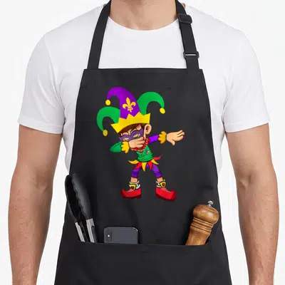 Dabbing mardi gras aprons - Cartoon jester in purple green and red doing a dab pose with mask and hat — shown on a black cotton canvas apron against a white background