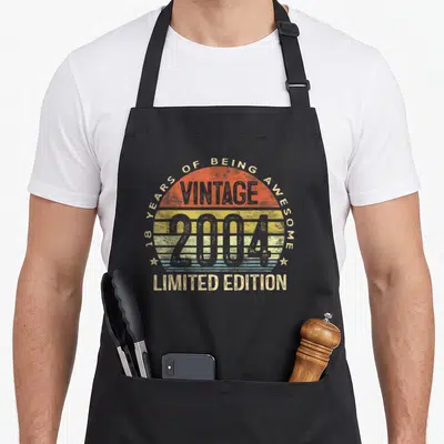 Limited edition 18th birthday apron - Retro striped sunset graphic with 18 years of being awesome text and two stars — shown on a black cotton canvas apron against a white background