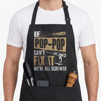 Screwed grandpa apron - Stacked text IF POP-POP CAN'T FIX IT WE'RE ALL SCREWED with screwdriver drill and screws — shown on a black cotton canvas apron against a white background