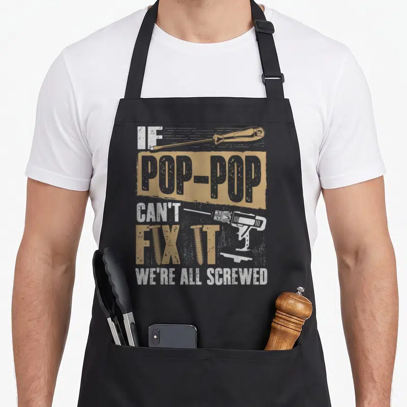 Screwed grandpa apron - Stacked text IF POP-POP CAN'T FIX IT WE'RE ALL SCREWED with screwdriver drill and screws — shown on a black cotton canvas apron against a white background