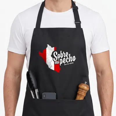 Sobre pride apron - Distressed map of Peru in red and white with Spanish text Sobre mi pecho llevo tus colores — shown on a black cotton canvas apron against a white background