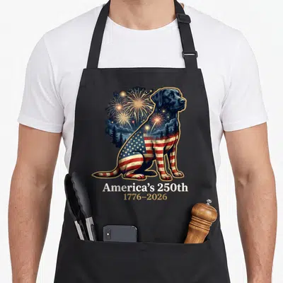 Americas labrador apron - Realistic black dog with US flag pattern and fireworks text America's 250th 1776-2026 — shown on a black cotton canvas apron against a white background