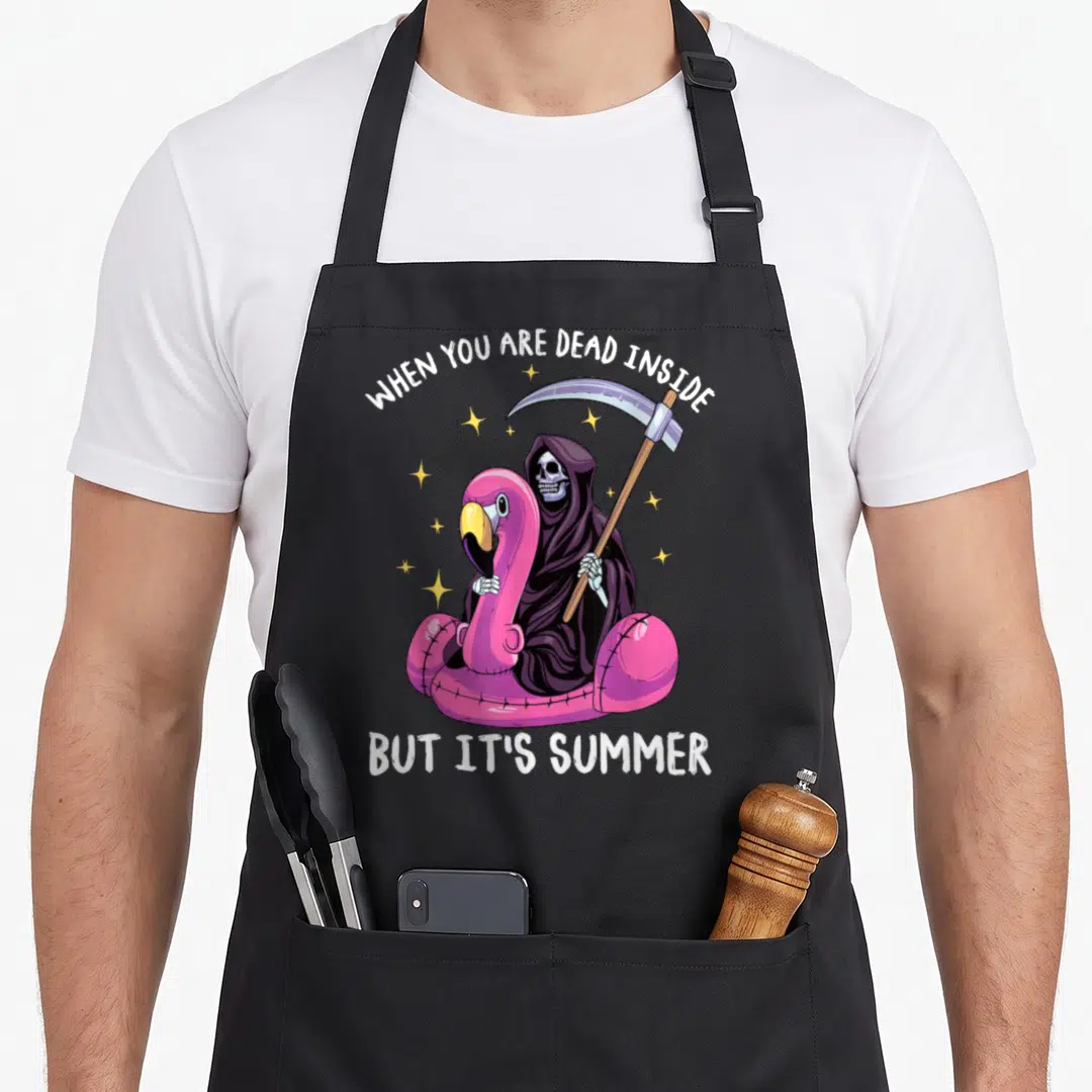 Wenn tot apron - Grim Reaper sitting on pink flamingo float holding scythe with white text and yellow stars — shown on a black cotton canvas apron against a white background