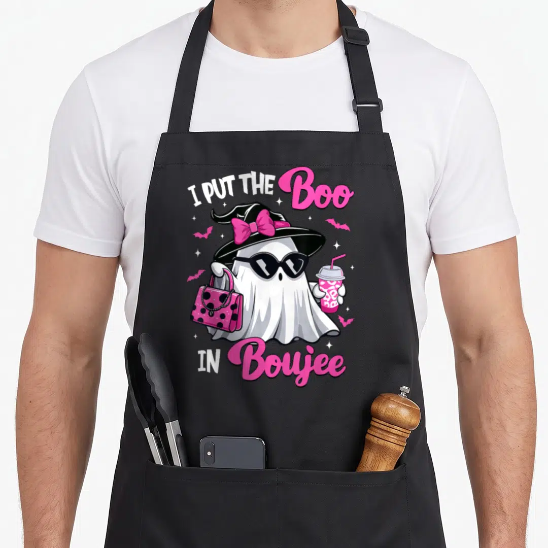 Boujee halloween apron - Cartoon ghost with sunglasses, pink bag, drink, and text I Put The Boo In Boujee — shown on a black cotton canvas apron against a white background