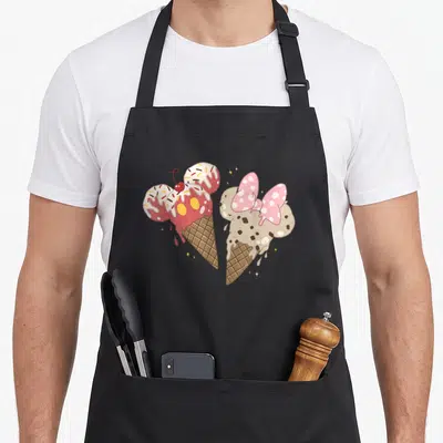 Friend ice cream apron - Two cartoon mouse-shaped ice cream cones with gold stars in pink beige and brown — shown on a black cotton canvas apron against a white background