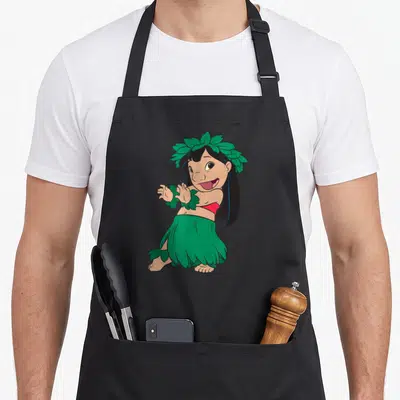 Hula dance apron - Cartoon girl wearing green leaf skirt, headpiece, and wrist cuffs with red top — shown on a black cotton canvas apron against a white background