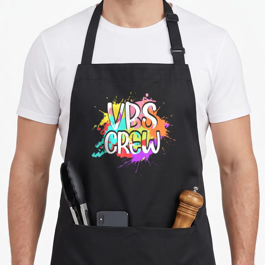 Vbs paint apron - VBS CREW white text over yellow blue red purple paint splatter design — shown on a black cotton canvas apron against a white background