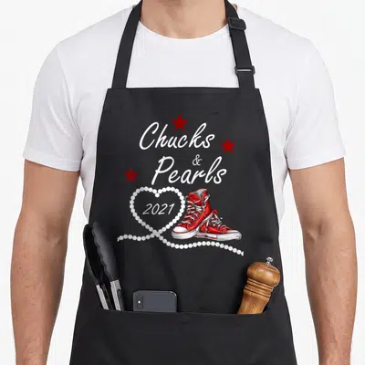 Blue pearls apron - Red sneakers, white Chucks & Pearls 2021 text, pearl heart, three red stars — shown on a black cotton canvas apron against a white background