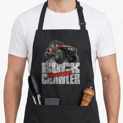 Rock car apron - Red and grey rock crawler vehicle over distressed ROCK CRAWLER text with BUILT TO ROCK overlay — shown on a black cotton canvas apron against a white background