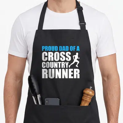 Proud cross country apron - Stacked white and blue text PROUD DAD OF A CROSS COUNTRY RUNNER with runner silhouette — shown on a black cotton canvas apron against a white background