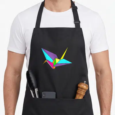 Colourful folding aprons - Multi-colored geometric origami crane in purple blue yellow green pink and orange — shown on a black cotton canvas apron against a white background