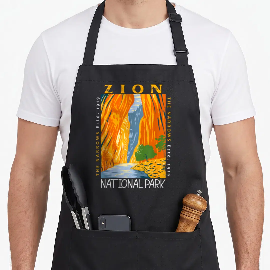 Zion utah girl apron - Retro orange canyon illustration with ZION and NATIONAL PARK text and vertical Established 1919 — shown on a black cotton canvas apron against a white background