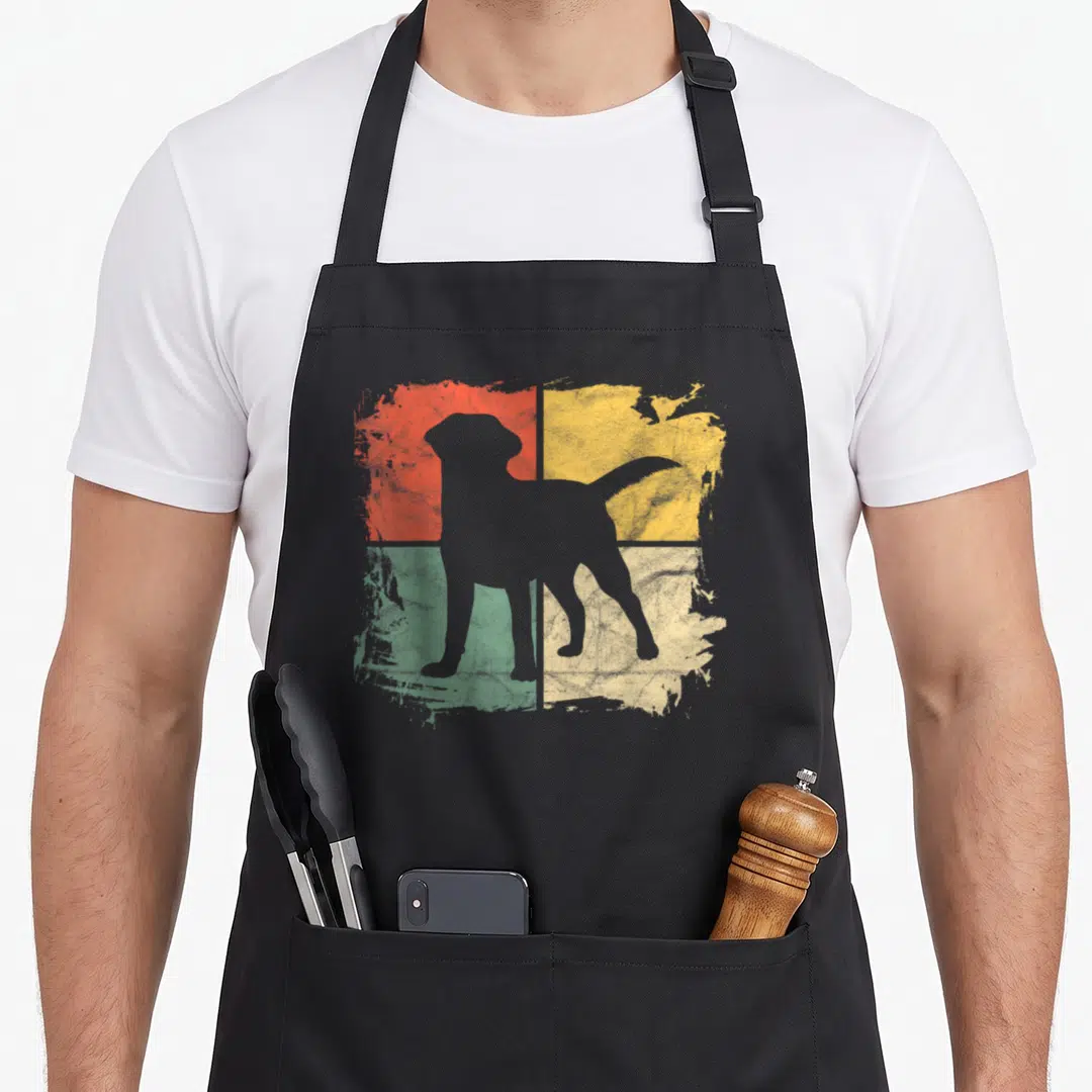 Square labrador apron - Grey dog silhouette over distressed red yellow green beige four quadrant blocks — shown on a black cotton canvas apron against a white background