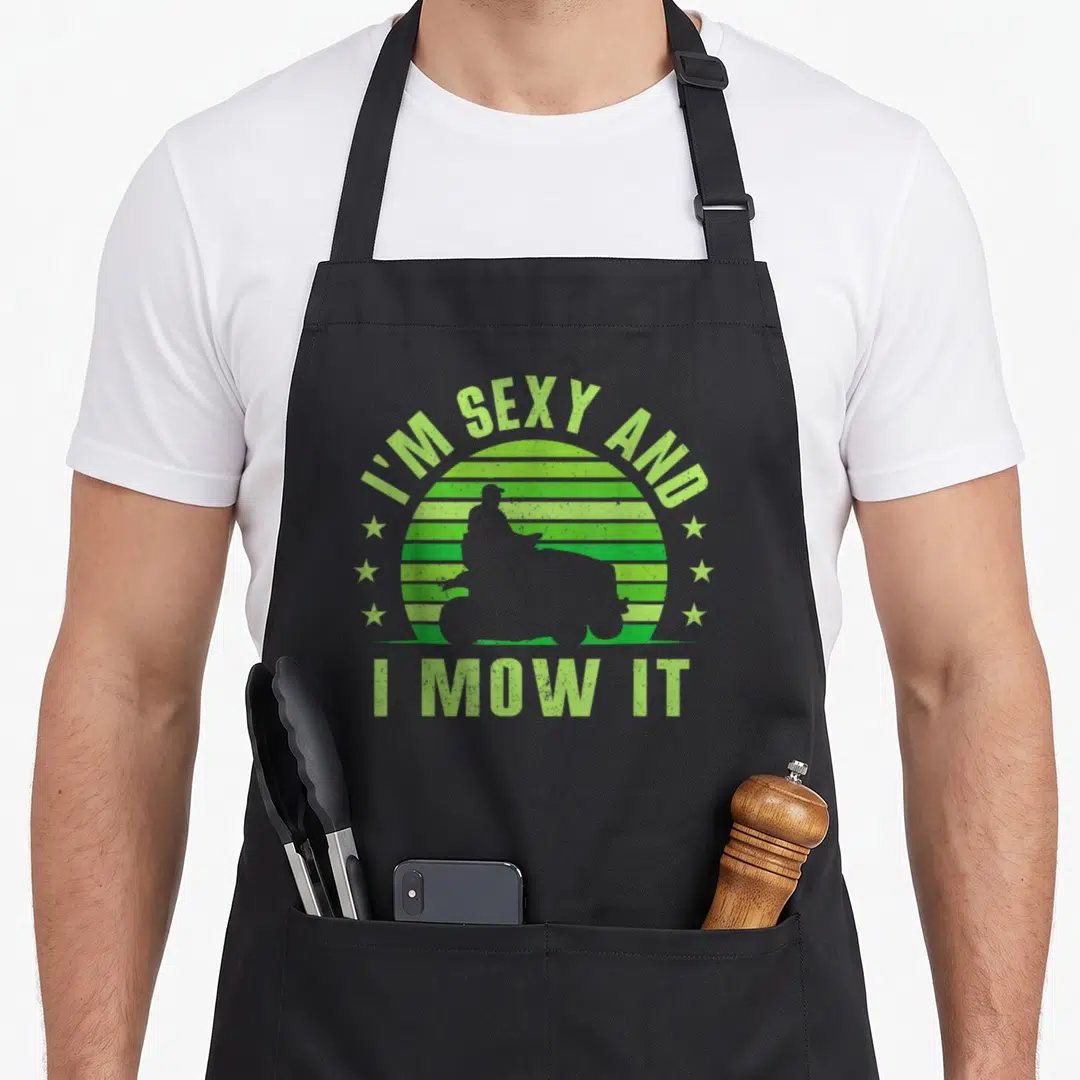 Mowing lawn apron - Retro lime green striped sun with dark grey riding mower silhouette and arched text — shown on a black cotton canvas apron against a white background